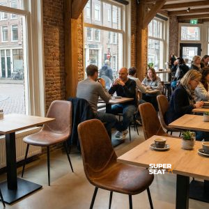 Super-Seat | Charlie vintage leren kuipstoelen cognac Leren stoelen in cognackleur, houten tafels, grote ramen en planten creëren een warme sfeer. | Horecameubilair