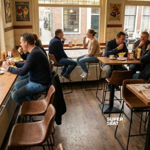 Super-Seat | Charlie vintage leren barkrukken cognac | Houten tafels, leren cognac barkrukken bij houten vloer en grote ramen in daglicht. | Horecameubilair