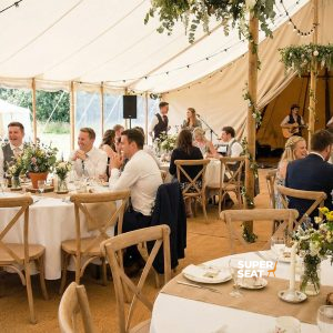 Super-Seat | Houten stoelen en tafels in lichte tinten, rond met bloemen, feestelijk onder tent. | Horecameubilair