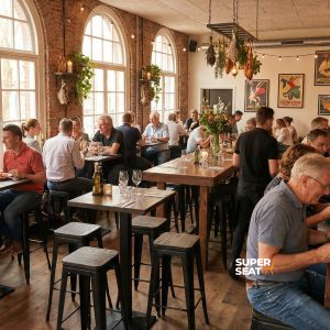 Super-Seat | Houten tafels, Lix barkrukken mat zwart hout, veel licht, bakstenen muren en groene planten. | Horecameubilair