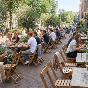 Super-Seat | Braune Holztische, alte hölzerne Terrassenstühle auf der Straße, Sonnenschein und Blumen. | Catering Möbel