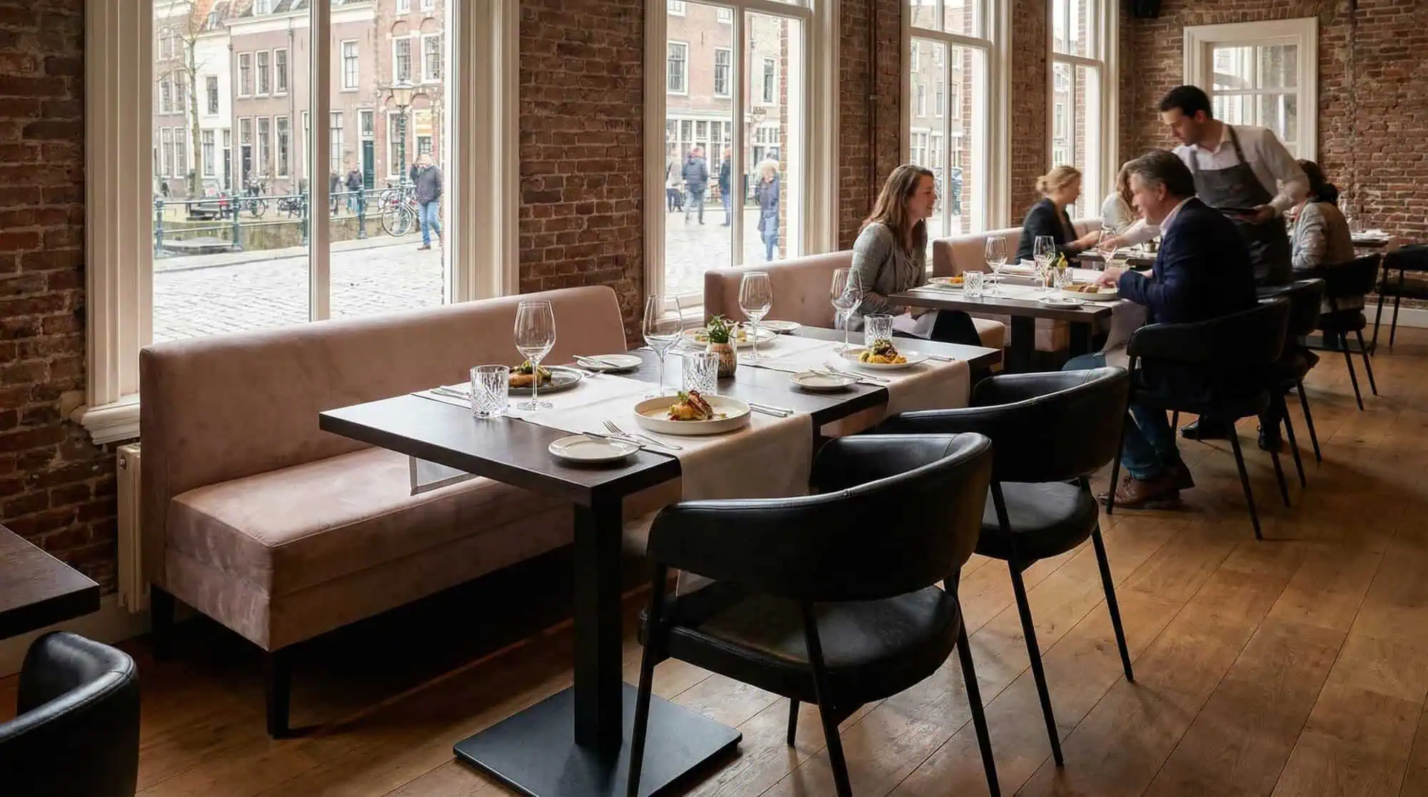 Super-Seat | Schwarze Maxwell-Stühle aus Stoff und Metall, Holztische, Backsteinwand in sonnigem Restaurant. | Catering Möbel