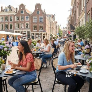 Super-Seat |Braune HPL-Kupfer-Catering-Tische 70x70cm mit schwarzen Metallstühlen in einer gemütlichen Straße. | Catering Möbel