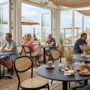 Super-Seat | Schwarze Stühle und Barhocker um schwarze HPL-Rost/Kupfer-Tische, Blick auf Dünen und Meer. | Catering Möbel