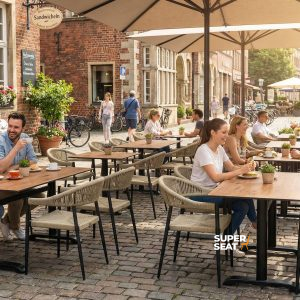 Super-Seat | Sie sehen Terrassentische aus Teakholz, Metallstühle, Blumenkästen und große Sonnenschirme auf einer gepflasterten Straße. | Catering Möbel