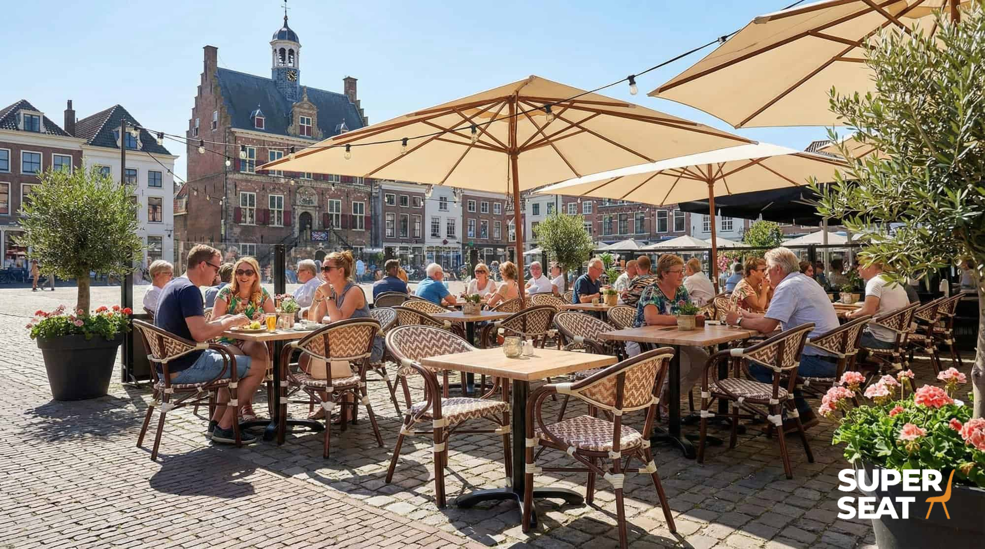Super-Seat | Marylin Parisian Hospitality Terrasse | Boho beige Stühle, Sessel und Holz-/Metalltische auf einem Kopfsteinpflasterplatz mit Sonnenschirmen. | Catering Möbel