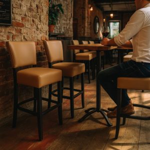 Super-Seat | In einem rustikalen Restaurant mit freiliegenden Ziegelwänden | Warme houten tafel, taupe kleurige barkrukken van bekleed met stof en metalen frame, houten vloer |. | Horecameubilair