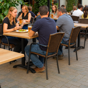 Super-Seat | Catering-Terrassentische Werzalit Eiche 120x70cm | Houten tafels en stoelen, bruin eiken, metalen onderstel, groene planten op bakstenen terras. | Horecameubilair