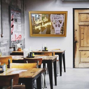 Super-Seat | Ein Café-Interieur mit Holztischen, Stühlen und Neonkunstwerken | Houten tafels en stoelen; barkrukken; kunstleren bekleding; goudkleurige lijst. | Horecameubilair