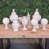 Super-Seat | Das Porzellan-Deko-Set Elegance 9-teilige Kollektion | Weiße Keramik auf Holztisch vor grüner Blätterwand. |. | Catering Möbel