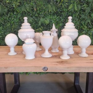 Super-Seat | Das Porzellan-Deko-Set Elegance 9-teilige Kollektion | Weiße Keramik auf Holztisch vor grüner Blätterwand. |. | Catering Möbel