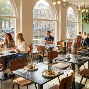 Super-Seat | Schwarze Tische in Marmoroptik, Holzstühle, Pflanzen, heller Raum mit großen Fenstern. | Catering Möbel