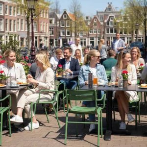 Super-Seat | Schwarze HPL-Tische, Metallstühle, Menschen, die draußen zwischen Blumen und Fahrrädern essen. | Catering Möbel