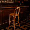 Super-Seat | A Vienna Thon No 18 Holzbarhocker Natur | Natuurlijke houten barkruk voor donkere bar; lichte kleur, hout; stijlvol op zwart-wit tegelvloer. | Horecameubilair