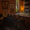 Super-Seat | Eine gemütliche Bareinrichtung mit vier stapelbaren Jody Design-Barhocker für die Gastronomie in schwarz/braun am Holztresen | Zwarte en bruine stapelbare barkrukken van metaal en hout aan houten bar, warme sfeer door kunst, planten, lampen. | Horecameubilair