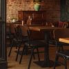 Super-Seat | Ein Restaurantinterieur mit leeren Holztischen und Jody Designstühle für die Gastronomie schwarz / braun stapelbar | Houten tafels en bruine/zwarte stapelbare stoelen van metaal/kunststof, groene lamp, warme sfeer. | Horecameubilair