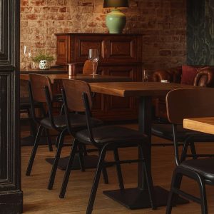 Super-Seat | Ein Restaurantinterieur mit leeren Holztischen und Jody Designstühle für die Gastronomie schwarz / braun stapelbar | Houten tafels en bruine/zwarte stapelbare stoelen van metaal/kunststof, groene lamp, warme sfeer. | Horecameubilair