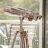 Super-Seat | Silbernes Chrom-Fernglas auf Holzstativ; im Hintergrund ein Holzstuhl, außen grün. | Catering Möbel