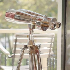 Super-Seat | Silbernes Chrom-Fernglas auf Holzstativ; im Hintergrund ein Holzstuhl, außen grün. | Catering Möbel